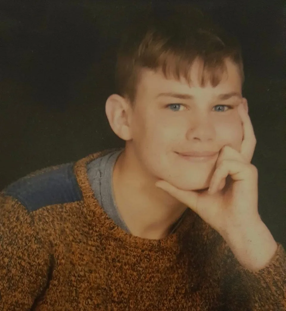 Timmy Boraston, smiling with his chin resting on his hand, in a knitted jumper.